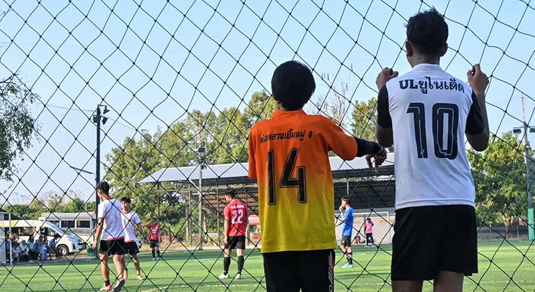 Två pojkar tittar ut mot en fotbollsplan.